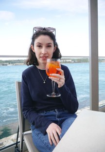 Blogger drinking aperol spritz by the ocean